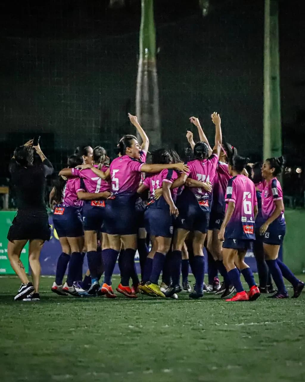 Atletas comemoram juntas em campo à noite