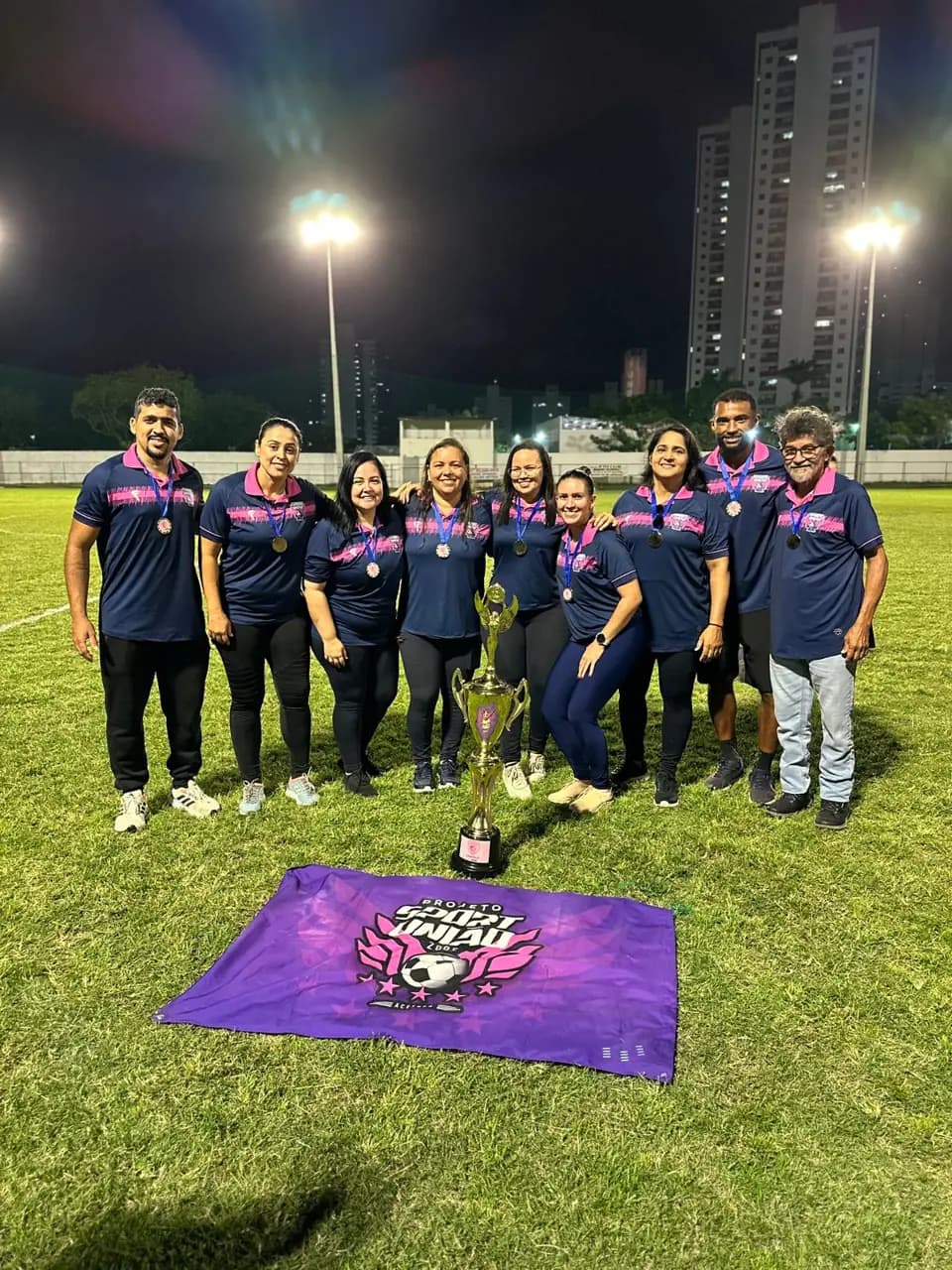 Coordenação do projeto Sport União reunida no campo com a bandeira da equipe
