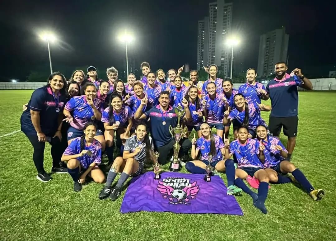Atletas do Sport União comemoram o título com troféus no gramado à noite